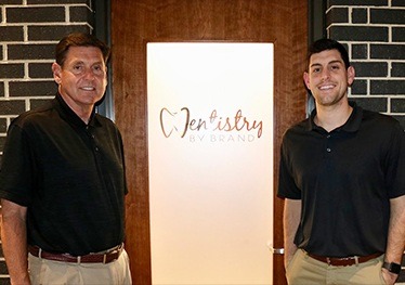 Dr. Craig and Dr. Kyle in front of Dentistry by Brand sign