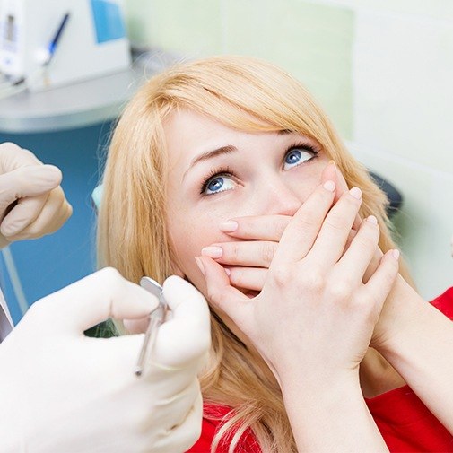 Fearful woman covering mouth at dentist