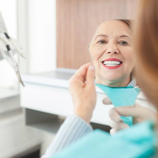 Older woman looking at smile in mirror