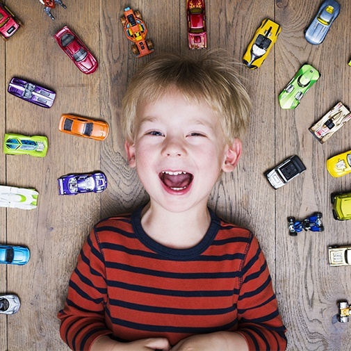 Laughing little boy surrounded by toy car