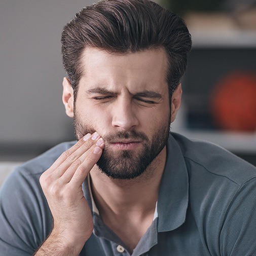 Man holding cheek in pain