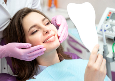 patient smiling while holding dental mirror