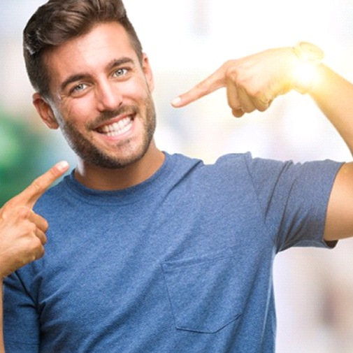 man with dental crowns in Garland pointing to his smile