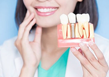 dentist holding a model of dental implants