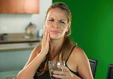 Woman with a toothache in Garland holding her cheek