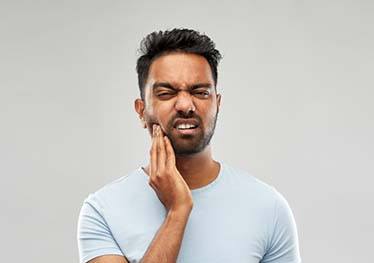 Man with a toothache in Garland holding his mouth