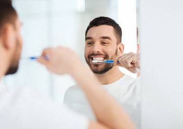 man brushing his teeth in front of a mirror 