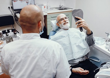 dental implant patient looking at his new smile in a mirror 