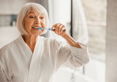 woman brushing teeth in bathroom mirror