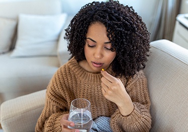 woman taking medication for dental implant post-op instructions in Garland