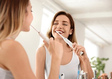 woman brushing teeth for dental implant post-op instructions in Garland