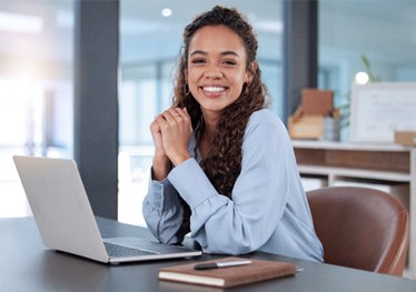 Woman smiling while working on laptop in office