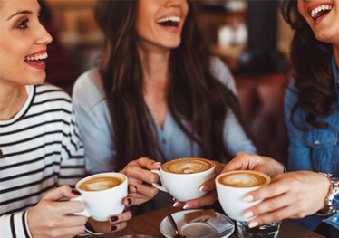Group of friends smiling while drinking coffee together