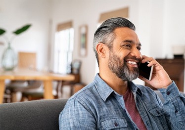 Smiling man talking on phone at home