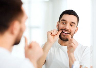  man flossing teeth in bathroom