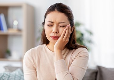 Closeup of woman holding her cheek due to tooth pain