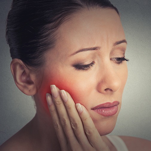 Woman holding cheek in pain