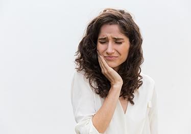 Woman in white blouse, experiencing mouth pain