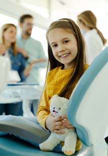 child smiling while dentist and parents discuss dental sealants