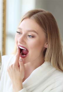 woman looking at her gums in handheld mirror