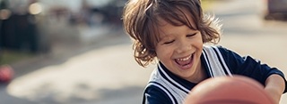 Laughing little boy holding basketball