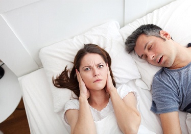 Husband snoring while wife covers her ears