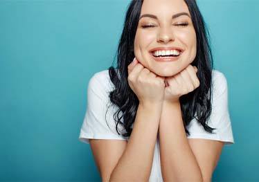 Woman on blue background smiling with veneers in Garland