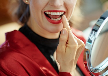 Woman examining cosmetic dentistry results in mirror