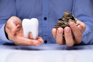 Two hands holding giant tooth and coins 