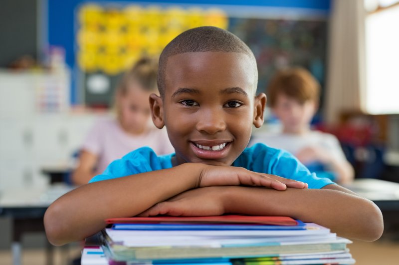 Child smiling in school after visiting a children’s dentist