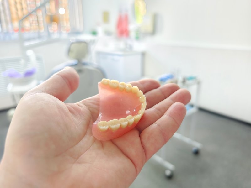 a person holding a full denture in their hand